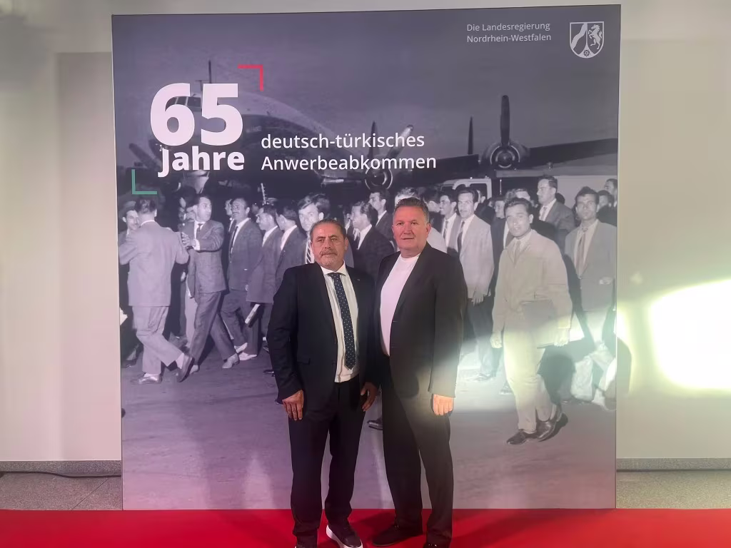 Hüseyin Erdoğan und Mustafa Yağcı vor dem Motiv zum 65. Jahrestag des deutsch-türkischen Anwerbeabkommens